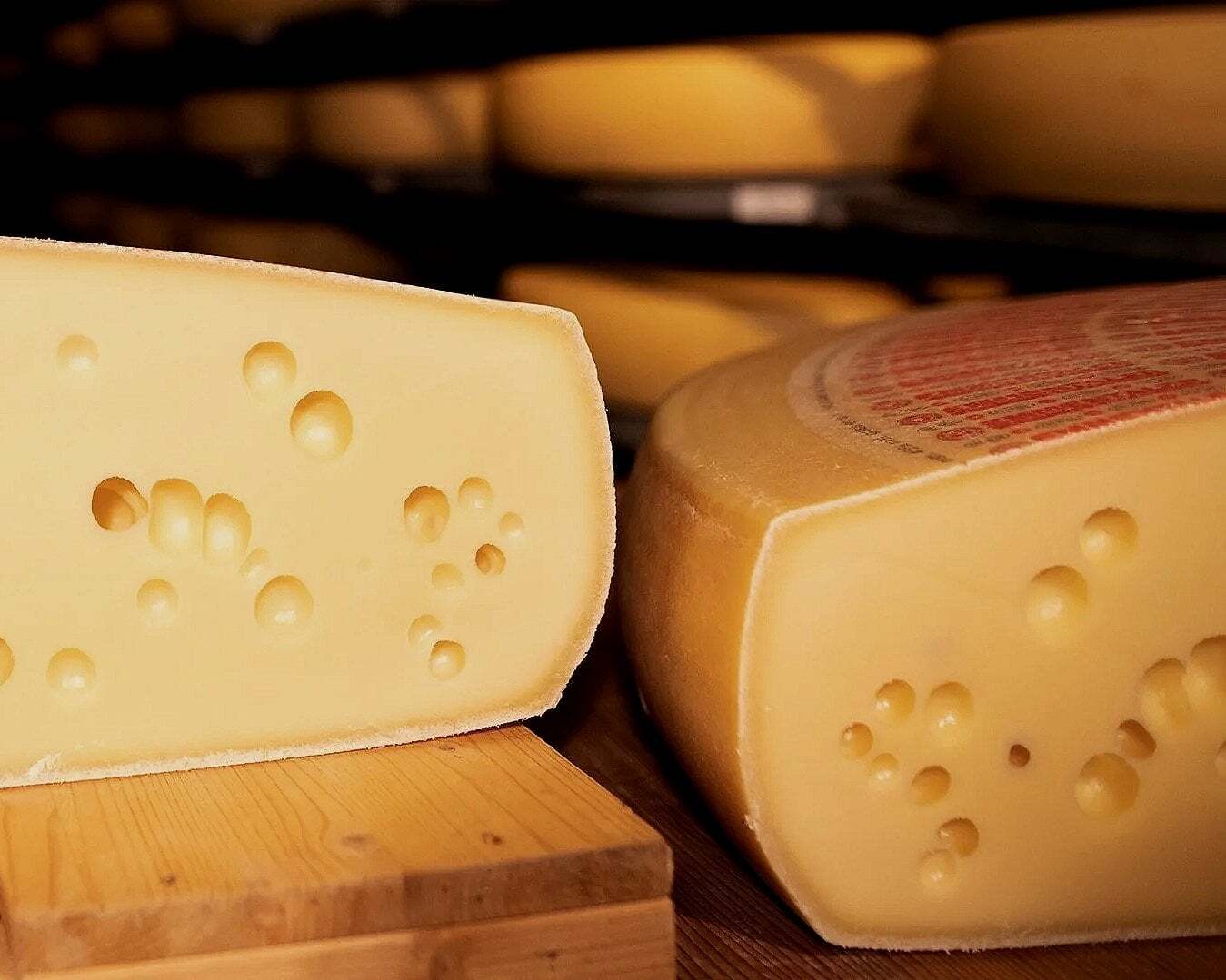 Emmentaler cheese wheels on wooden shelf